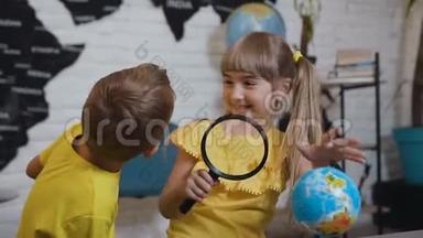 两个可爱的学生在教室里用<strong>放大镜</strong>有趣地<strong>学习</strong>地球仪的肖像。 在那儿